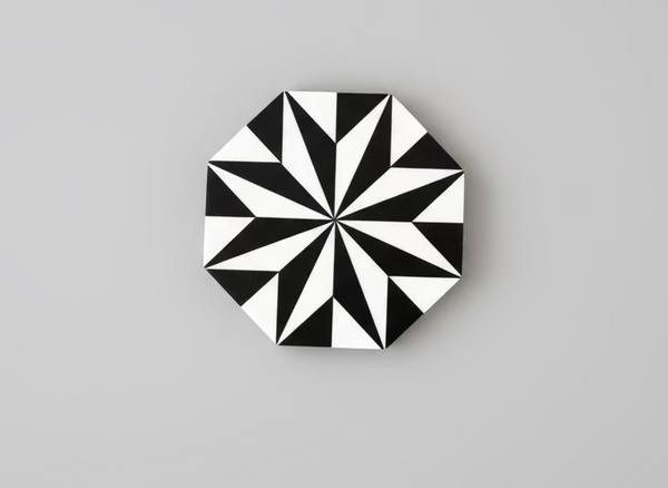 Black and white geometric patterned coaster on a gray background
