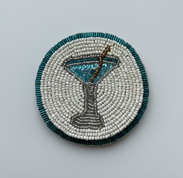 Beaded coaster with martini glass design on a reflective surface