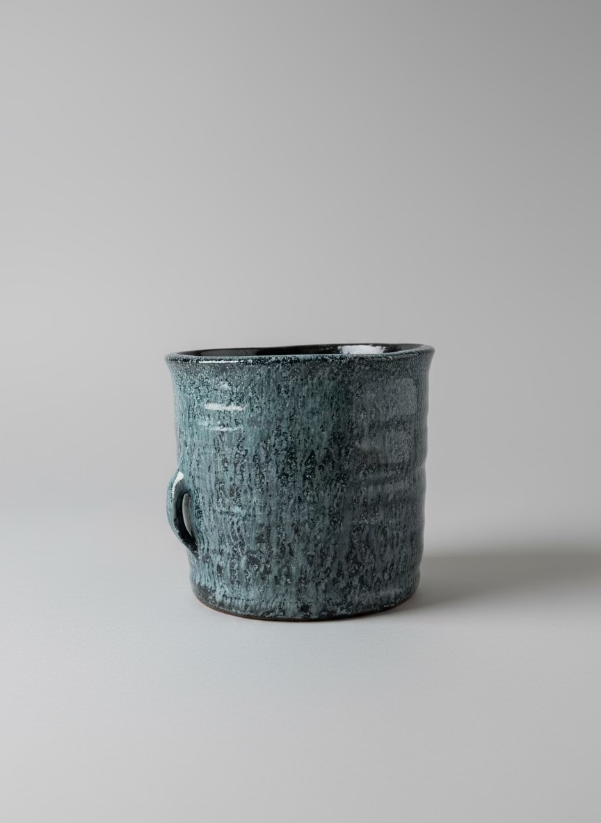 Black speckled mug on a white surface with a window in the background