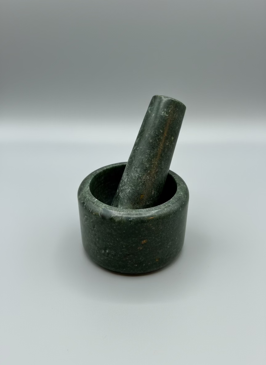 Green stone mortar and pestle on a clear plastic surface