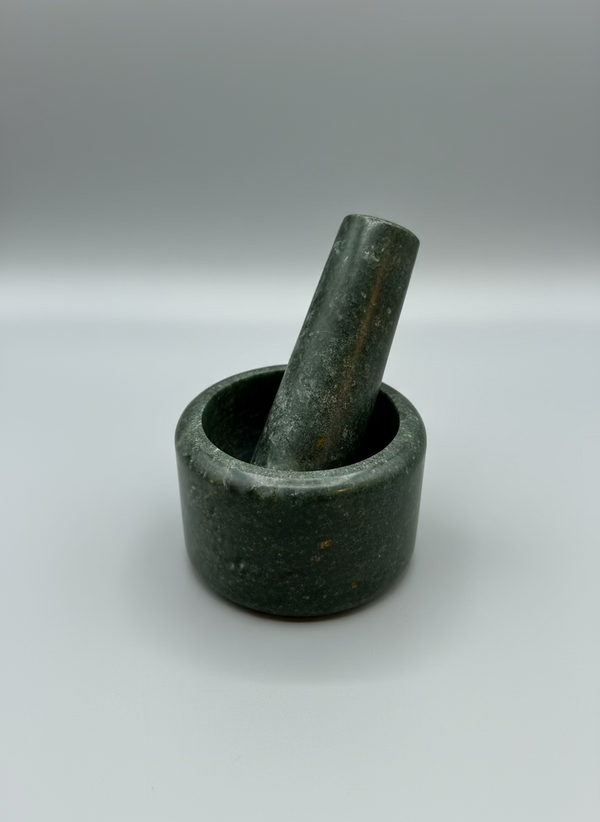 Green stone mortar and pestle on a clear plastic surface