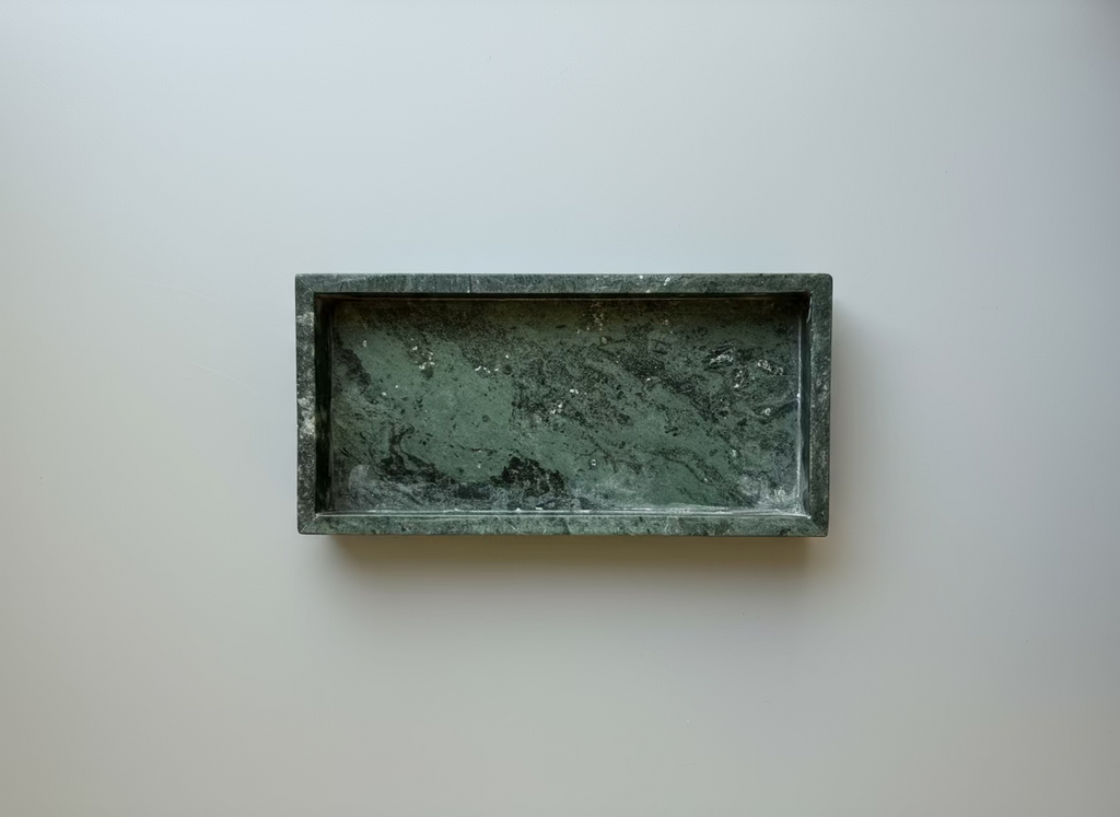 Rectangular green stone tray on a white surface with a clear container in the background.