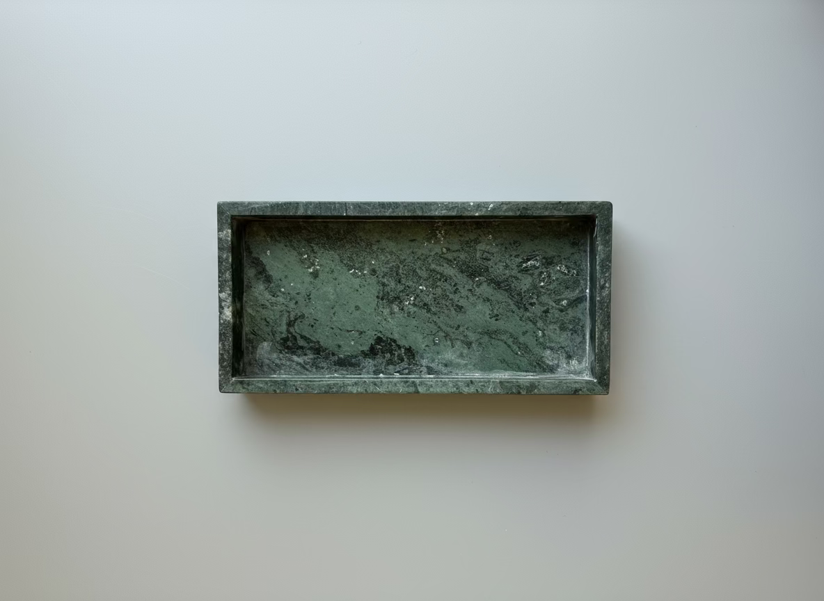 Rectangular green stone tray on a white surface with a clear container in the background.