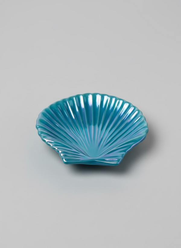 Blue glass shell dish on a black and white patterned book