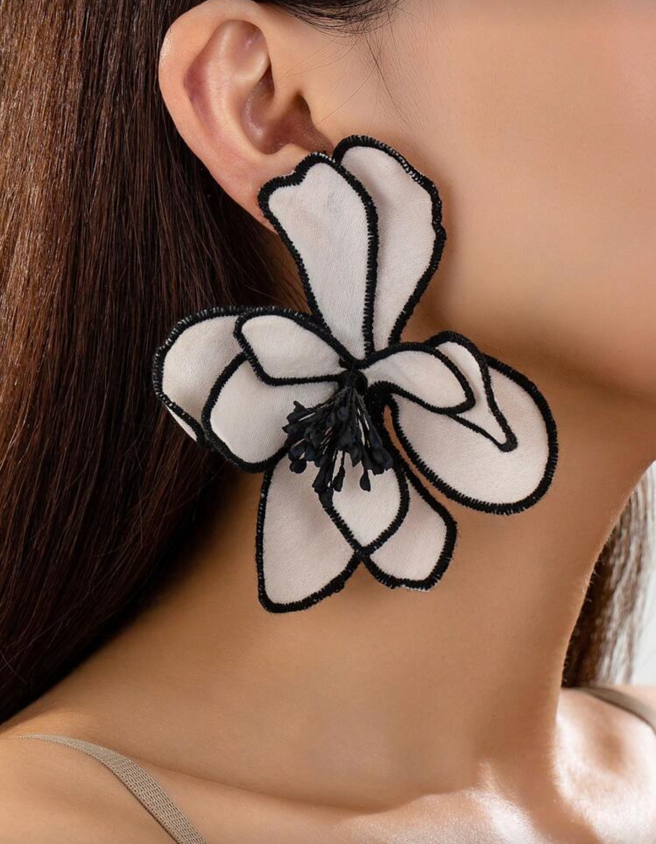 Exaggerated fabric flower earrings being worn on a model's ear.