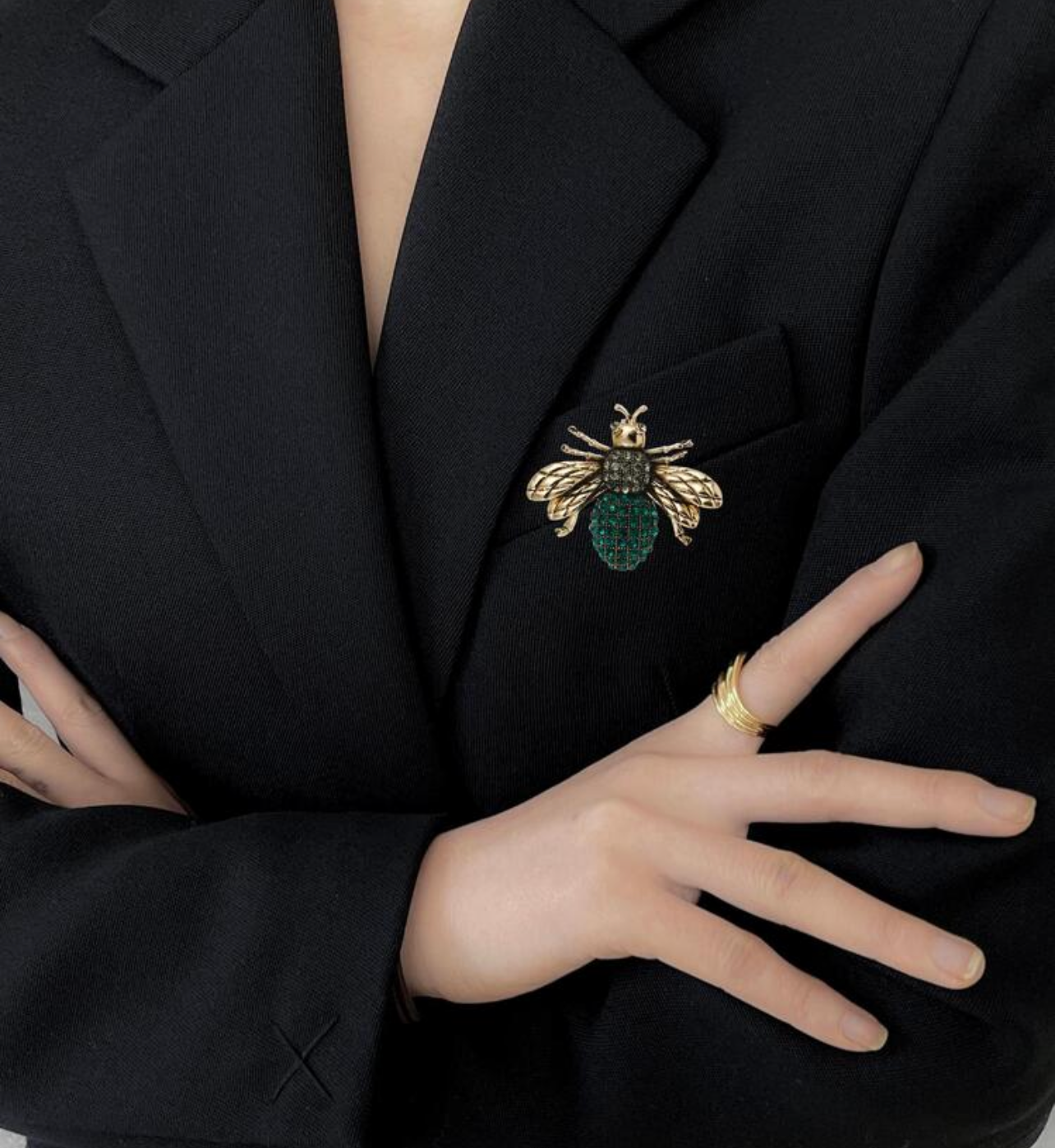 Person wearing a black blazer with a brooch, on a plain background